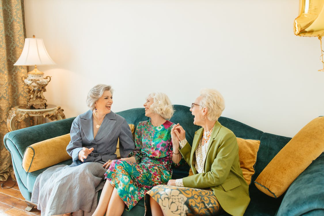 Older women sitting and laughing together on a couch.