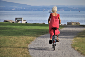A senior riding a bike along a path overlooking the sea