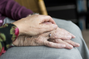 A senior’s hands folded in their lap