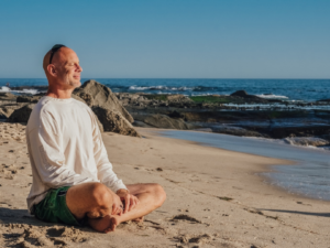 A senior meditating on the beach