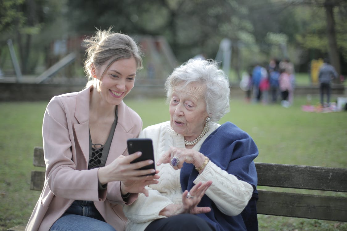 a person showing a smartphone to a senior. 