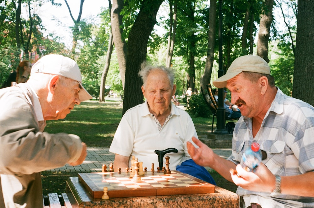 three seniors playing chess. 