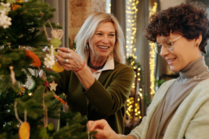 A senior decorating a Christmas tree with their caregiver