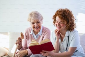 A senior and their caregiver reading a book